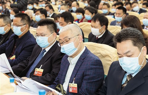 開幕大會上，政協(xié)委員認真聽取政協(xié)工作報告